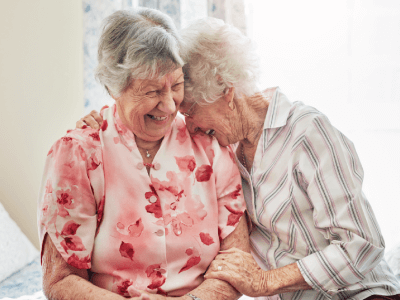 Two elderly women laughing together while sitting down